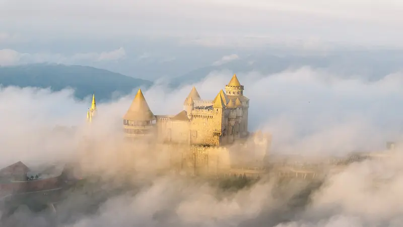 The fairy-tale castle at Fantasy Park, Bà Nà Hills, rising out of golden clouds