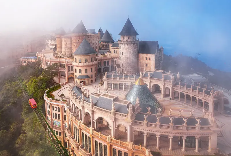 Castle towers and French-style buildings of Bà Nà Hills’ French Village in morning mist