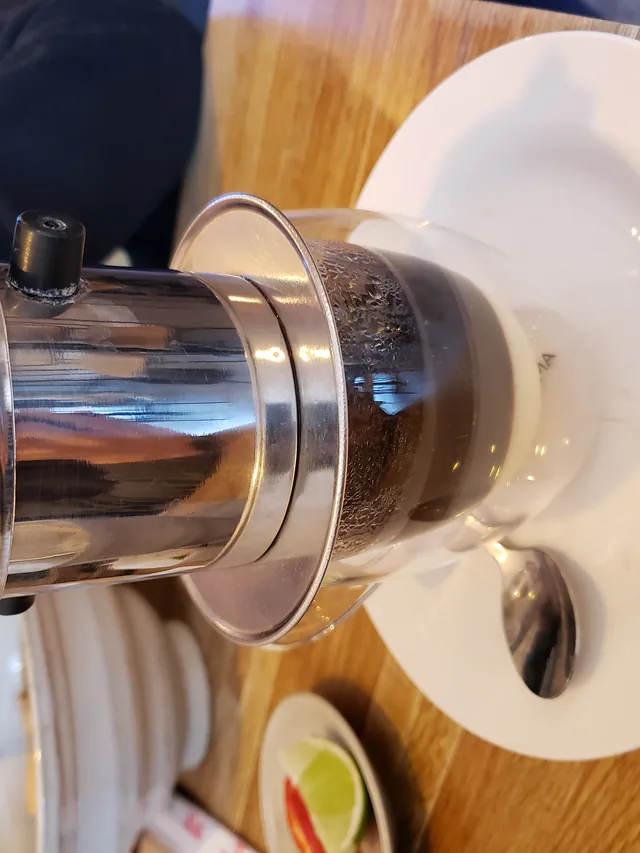 Vietnamese phin drip coffee brewing into a glass